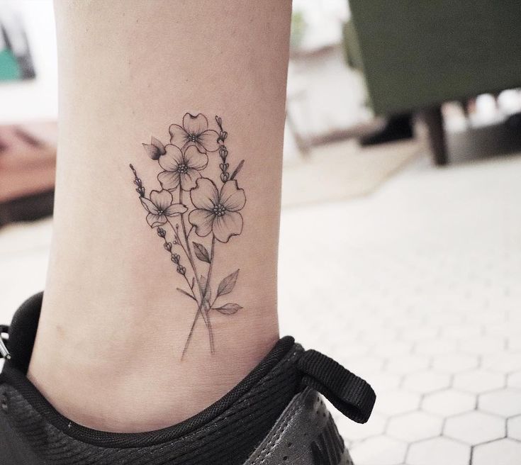 a small tattoo on the ankle of a woman's foot with flowers in it