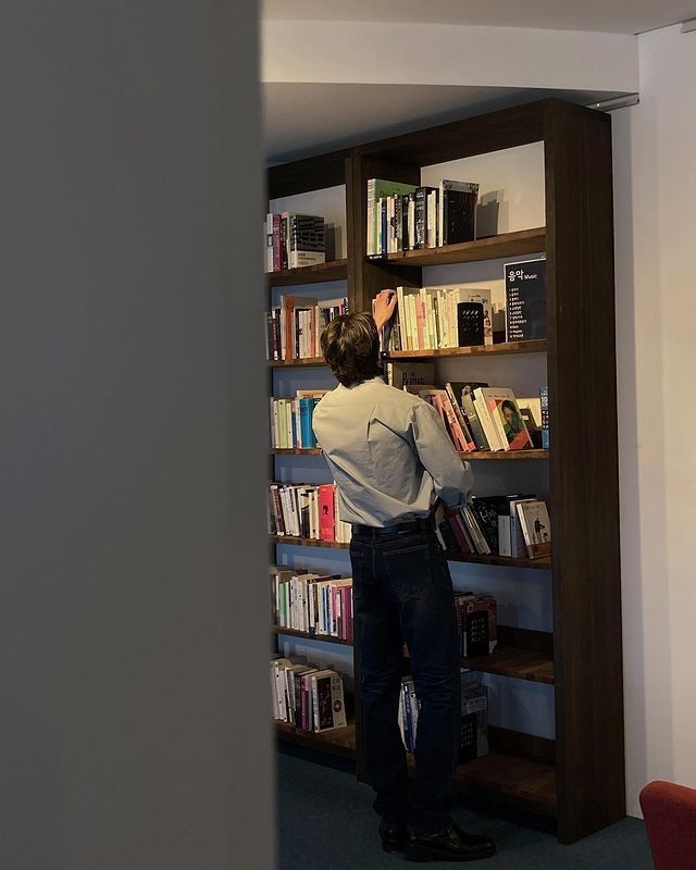 a man standing in front of a book shelf filled with books