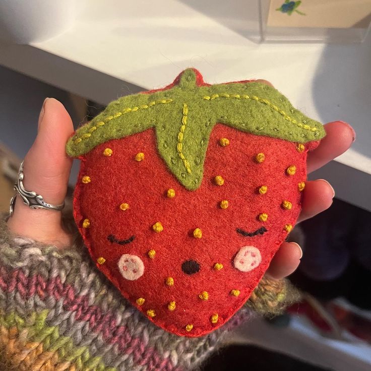 a hand holding a small red strawberry shaped object