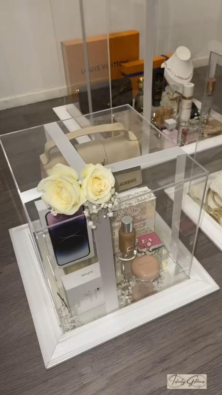 a glass display case filled with perfumes and flowers on top of a wooden floor