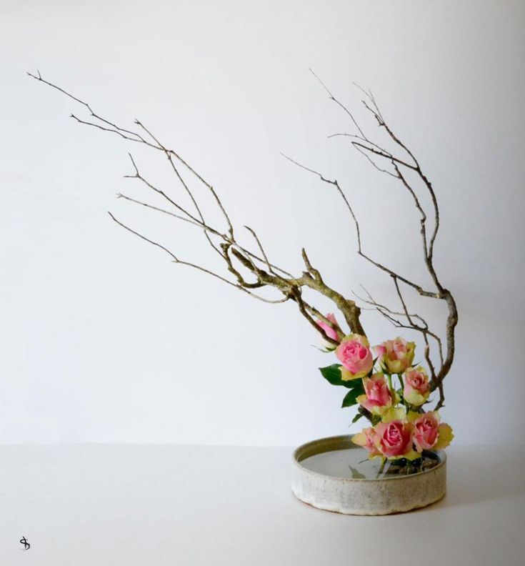 a vase filled with pink flowers on top of a white table next to a wall