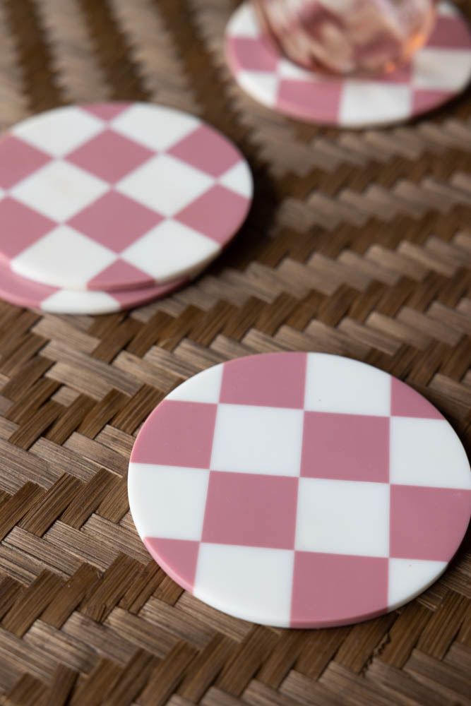 three pink and white checkered coasters sitting on a table