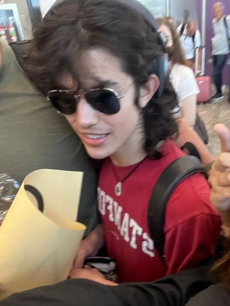 a young man with sunglasses is holding a piece of paper and giving the thumbs up