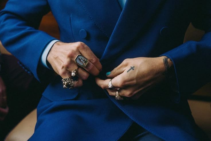 a man in a blue suit with his hands on the lapel of his jacket