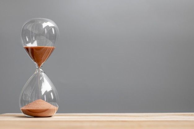 an hourglass sitting on top of a wooden table next to a red sand clock