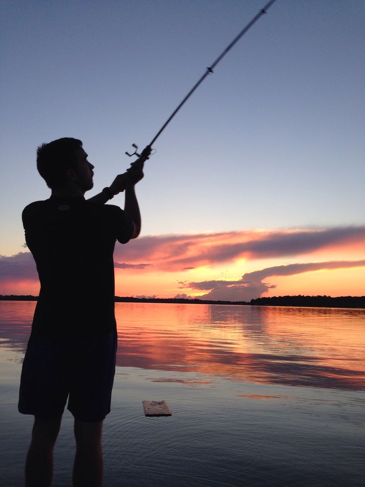 a man is fishing at sunset on the water