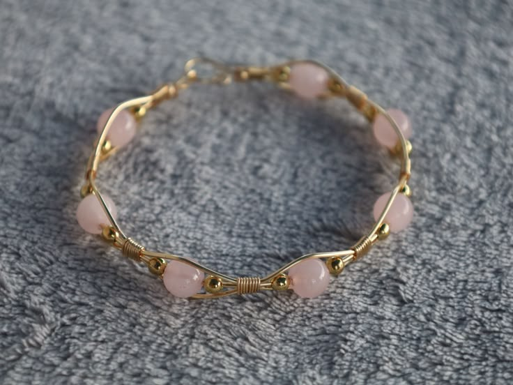 Check out this beautiful hand wrapped bracelet with a harmonious blend of elegance and charm. Genuine rose quartz beads, known for their soothing energy, are delicately accented by hand wrapped gold-colored wire (tarnish resistant copper wire). Elevate your style with the timeless beauty of natural gemstones and handcrafted artwork. How To Make Gemstone Bracelets, Wire Wrapped Beaded Bracelet, Gold Wire Bracelet, Bead Wire Bracelet, Braided Wire Bracelet, Dainty Wire Wrapped Jewelry, Cute Homemade Bracelets, Copper Bracelets Handmade, Wire Bracelet Ideas