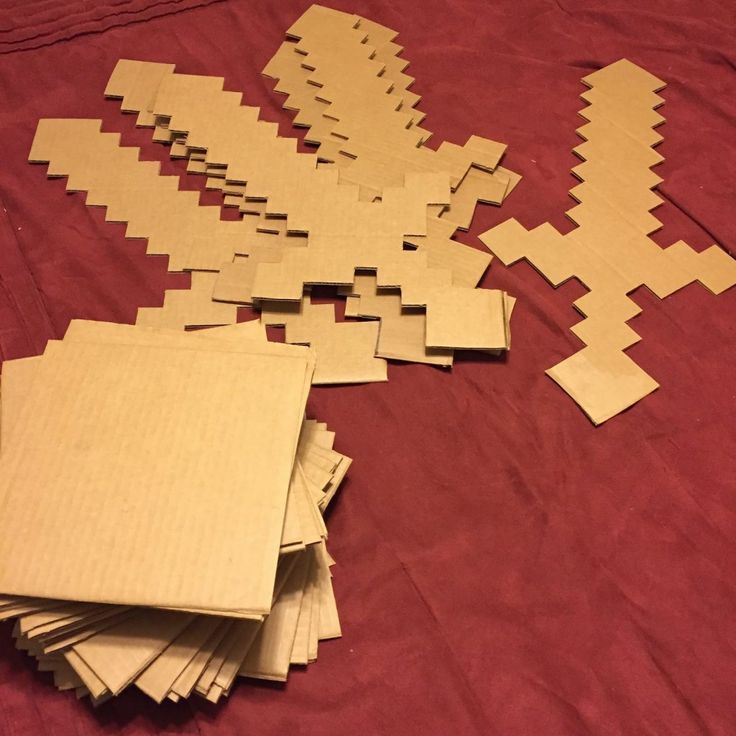 several pieces of wood sitting on top of a red cloth covered bed spread with squares and rectangles