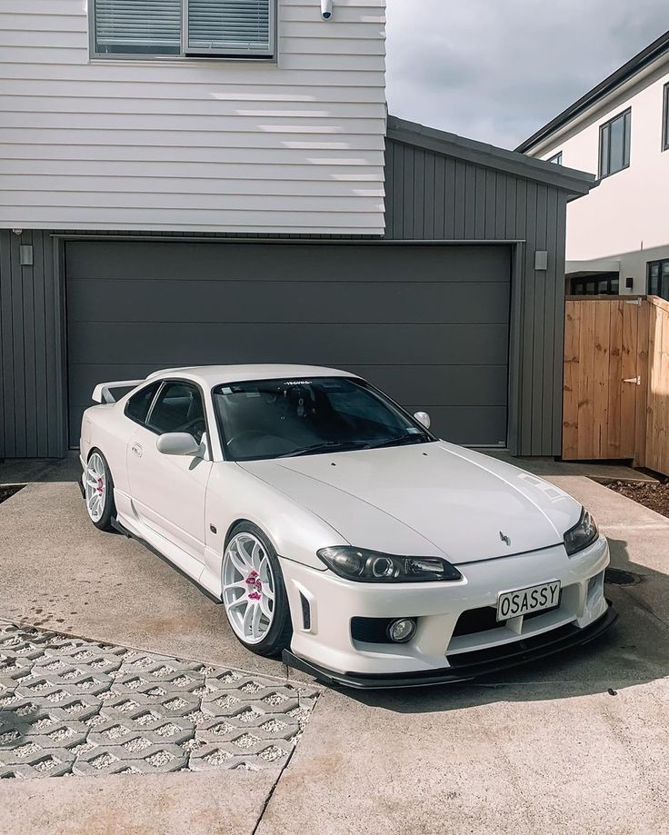 a white sports car parked in front of a house