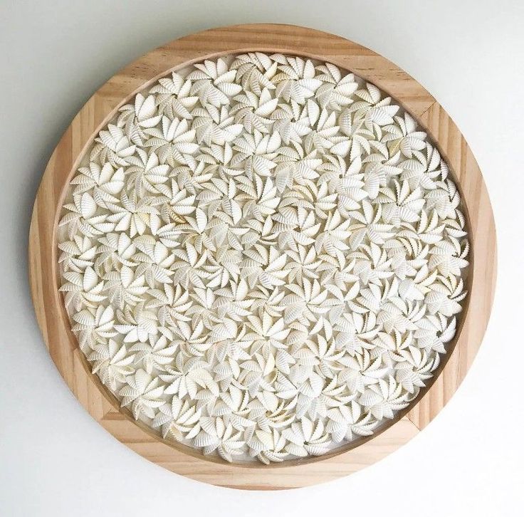 a wooden plate topped with white flowers on top of a table next to a wall