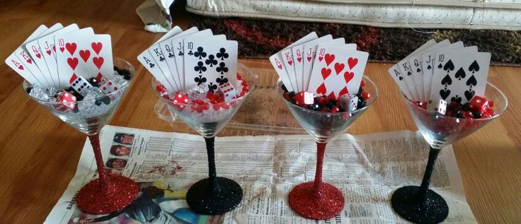 four wine glasses with playing cards in them sitting on a table next to a newspaper