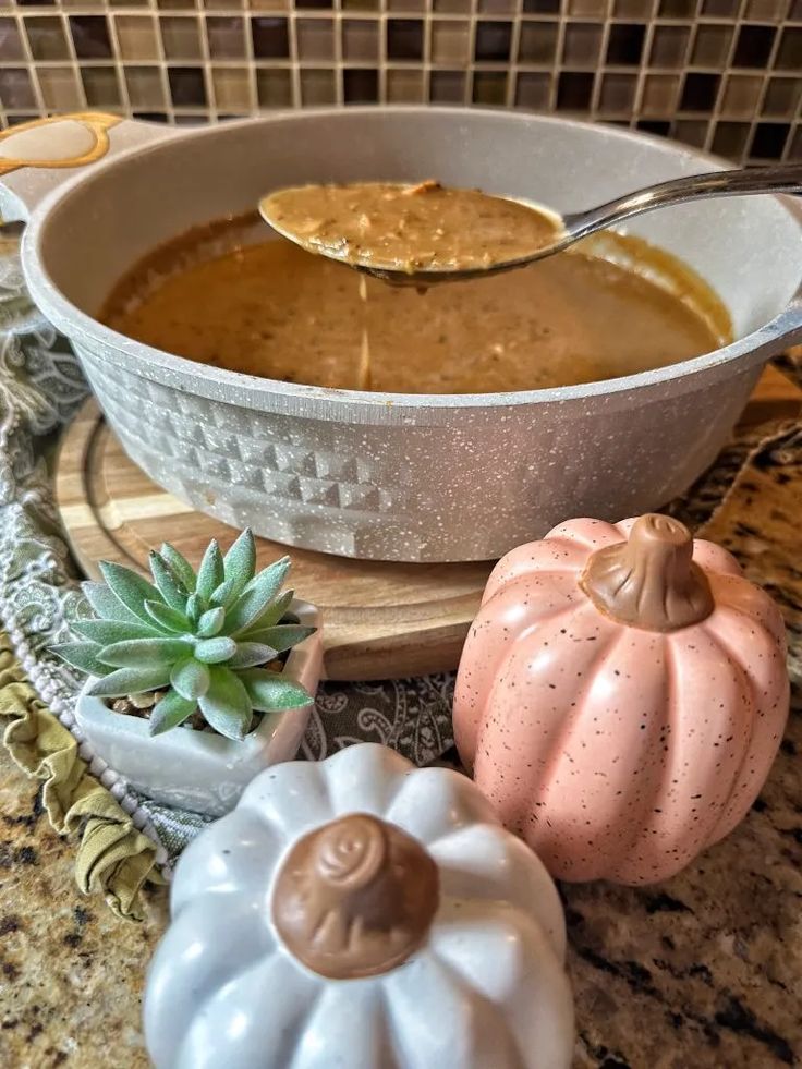 a bowl filled with soup next to two small pumpkins