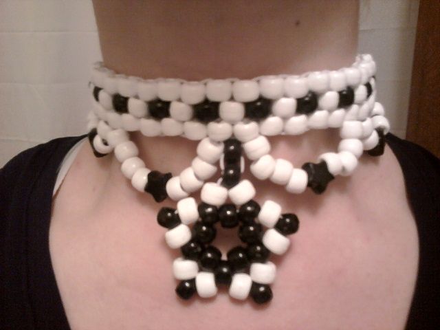 a woman wearing a black and white beaded necklace on her neck with beads attached to it