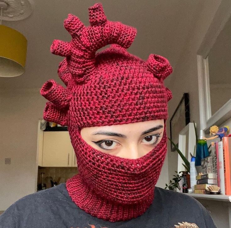 a woman wearing a red knitted hat and scarf with an animal on it's face