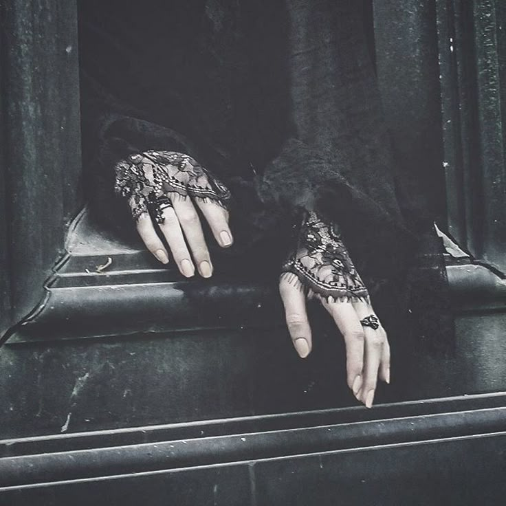 a woman's hands with black lace on them are resting on a metal box