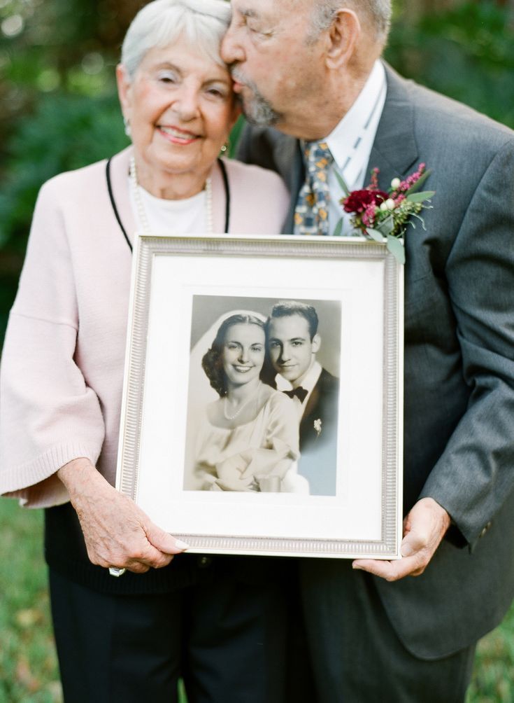 an older couple kissing each other while holding a framed photo in front of their face