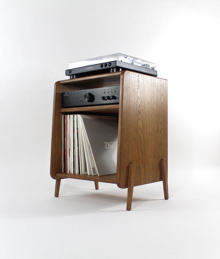 an old record player is sitting on top of a wooden stand with records in it