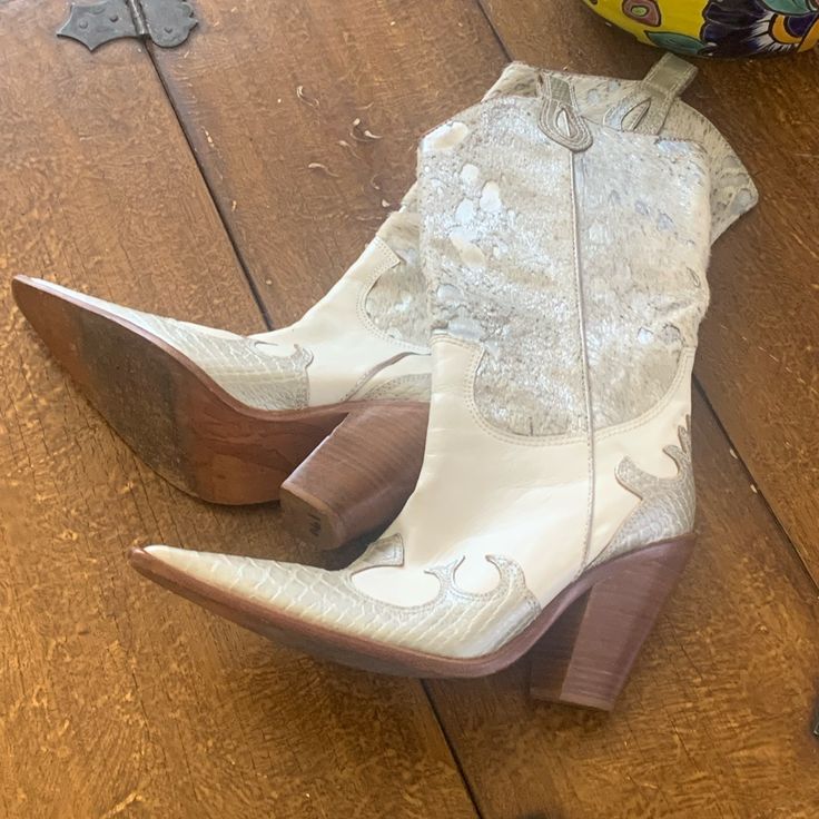 a pair of white cowboy boots sitting on top of a wooden floor