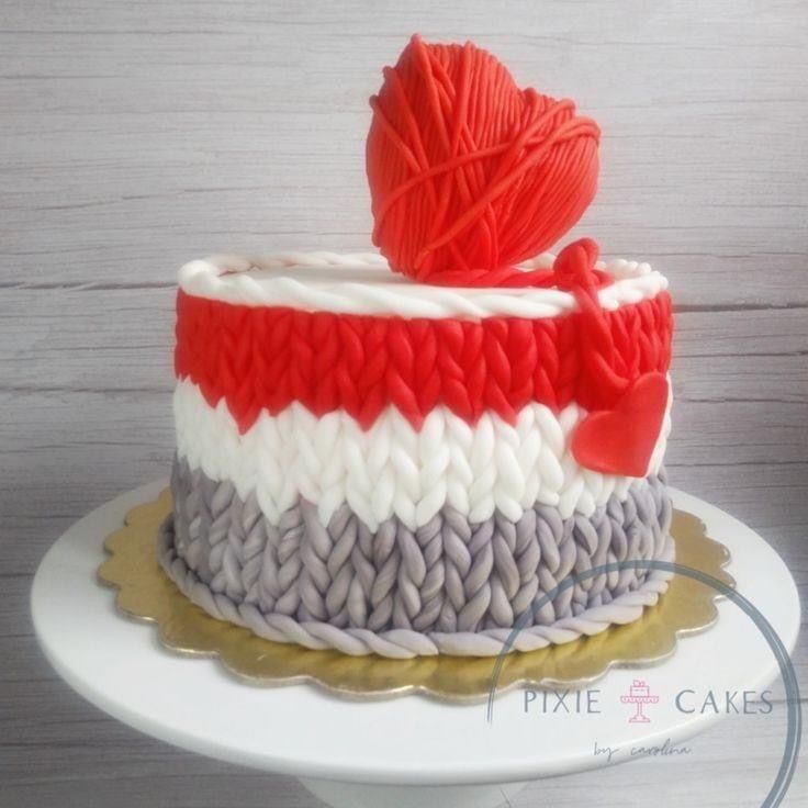 a cake decorated with red, white and grey yarn