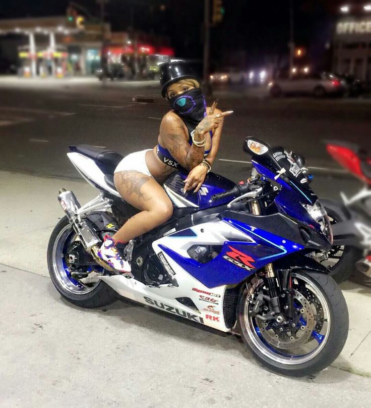 a woman sitting on top of a blue and white motorcycle