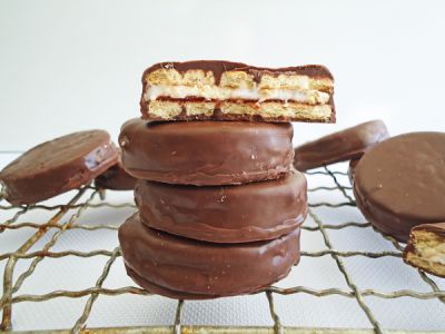 a stack of chocolate covered cookies sitting on top of a cooling rack with one cookie in the middle