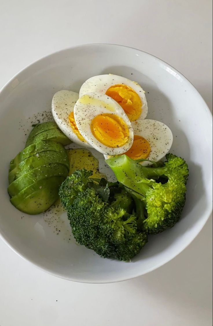 an egg and broccoli in a white bowl