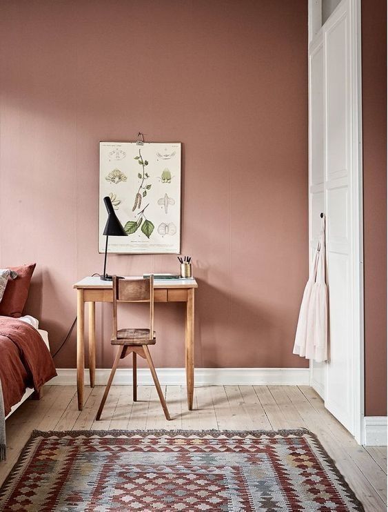 a bedroom with pink walls and a rug on the floor next to a bed in front of a painting