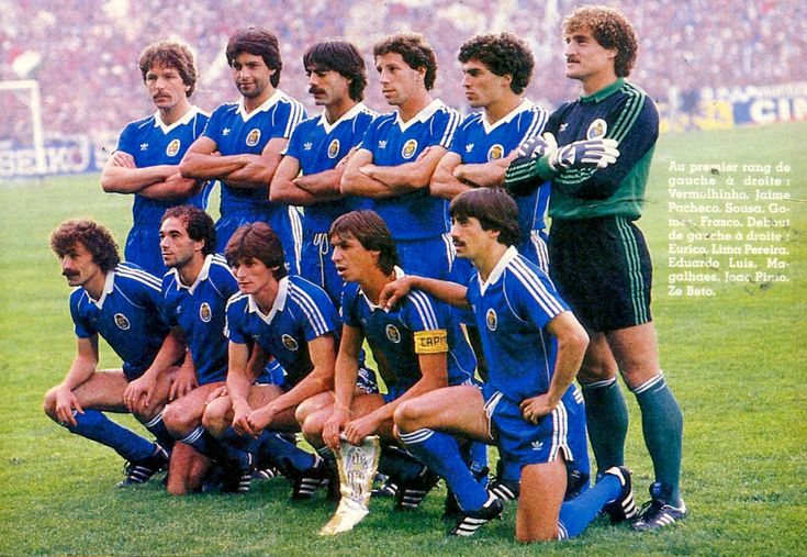 a group of soccer players posing for a team photo in front of an audience with their arms crossed