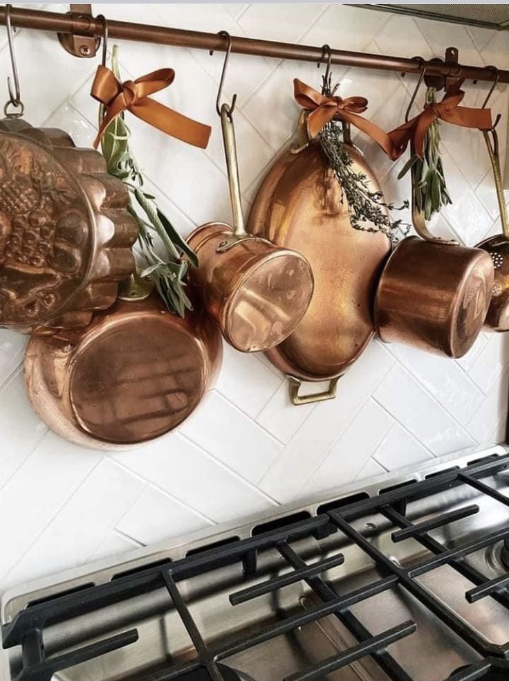 pots and pans are hanging on the wall above an oven with two burners