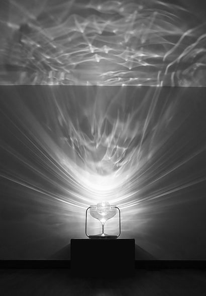 a black and white photo of an object in the middle of a room with light streaming through it