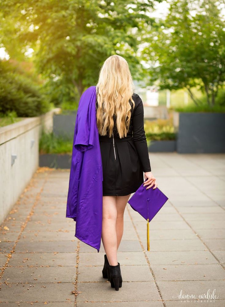 a woman walking down a sidewalk carrying a purple purse and a purple coat over her shoulders