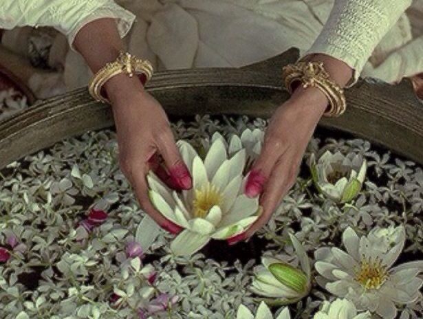 a woman is holding flowers in a pot with water lillies on the bottom floor