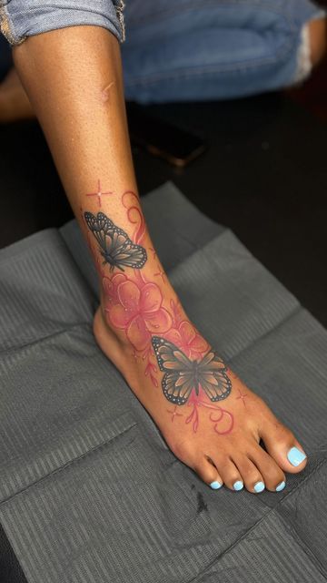 a woman's foot with butterfly tattoos on her left and pink flowers in the middle