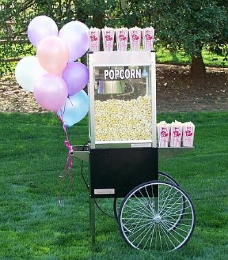 a popcorn cart in the grass with balloons