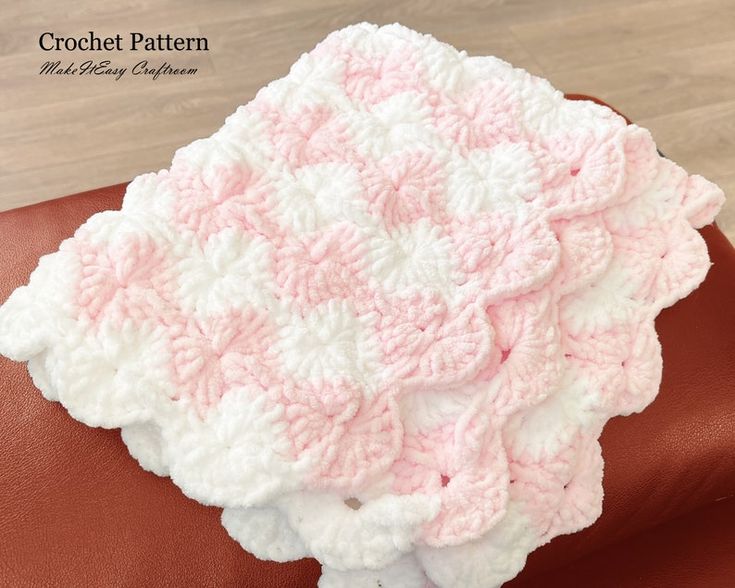 a pink and white crocheted dishcloth sitting on top of a brown leather chair