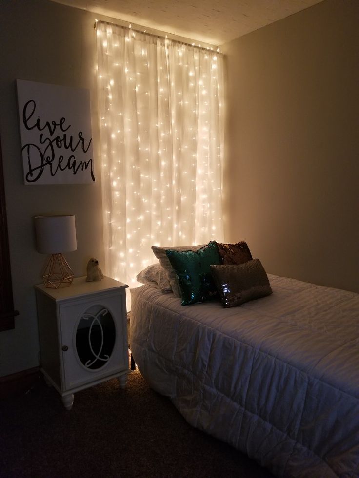 a bedroom with lights on the wall and a bed in front of a curtained window