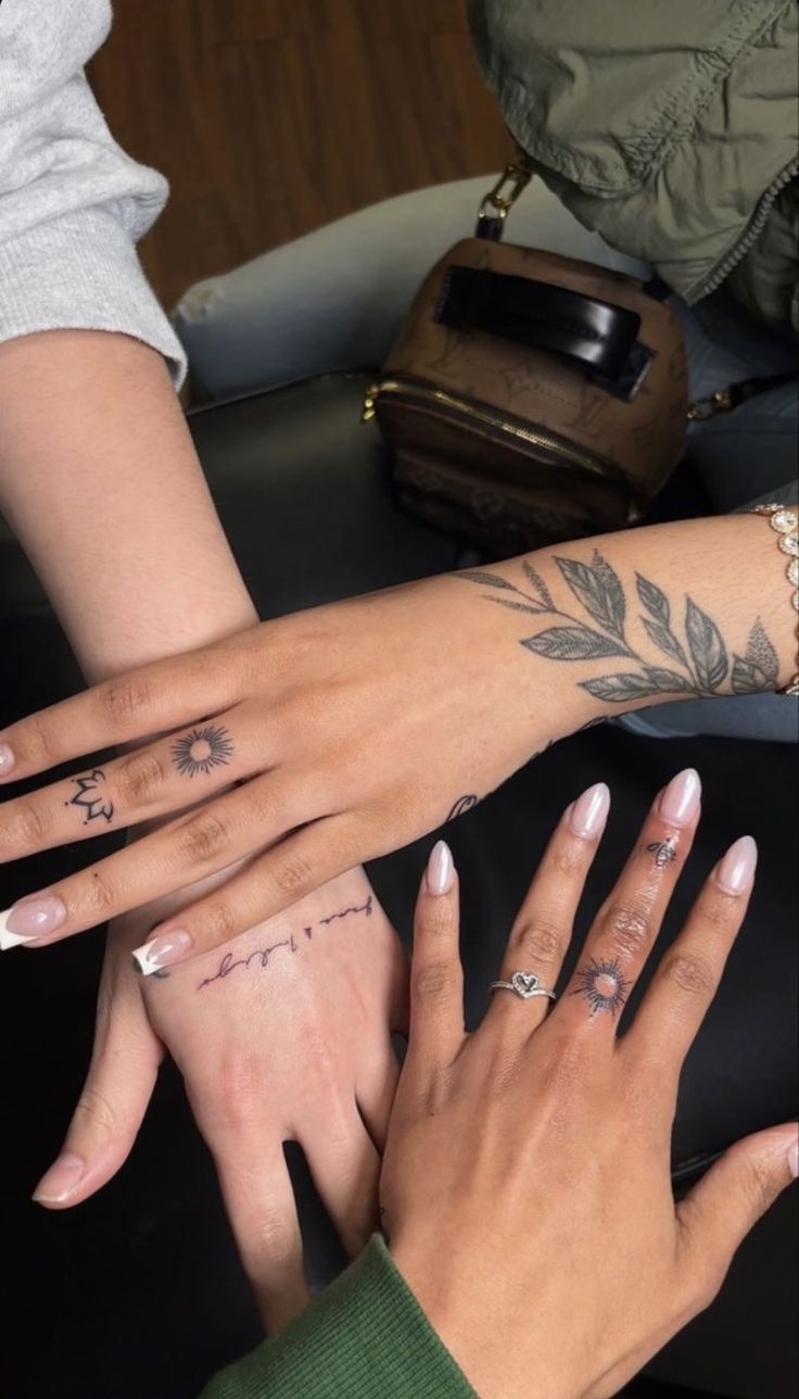 four people with their hands together holding each other's fingers and tattoos on their arms