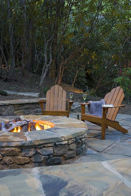 an outdoor fire pit with two chairs around it