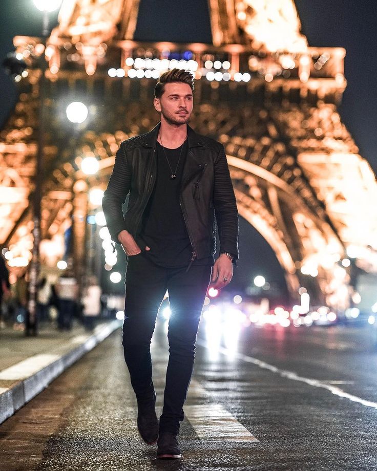 a man walking down the street in front of the eiffel tower at night