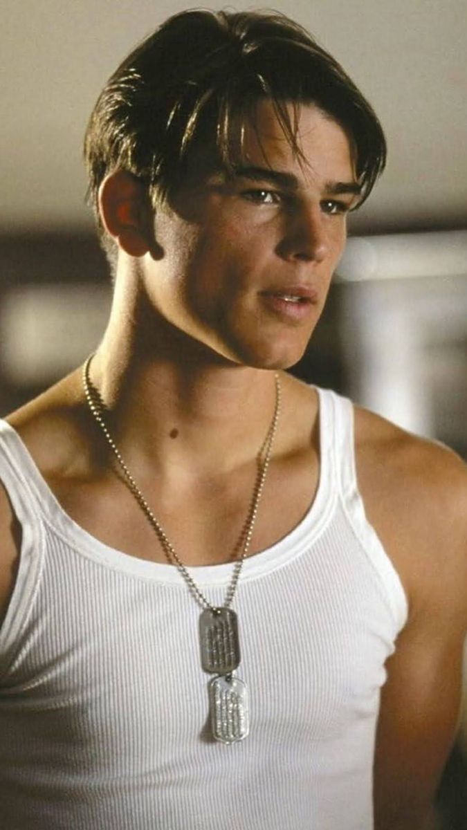 a young man wearing a white tank top with a chain around his neck and necklace