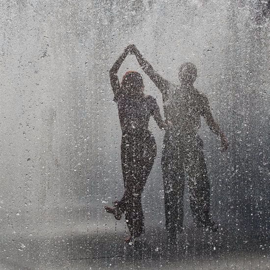 two people standing in front of a window with snow falling on them and the words below it