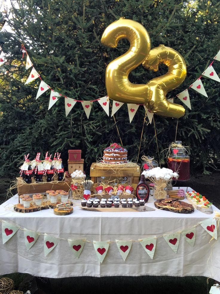 a table topped with lots of desserts and balloons in the shape of twenty two