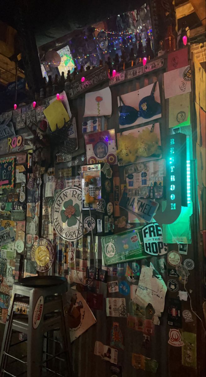 a wall covered in lots of different types of signs and magnets next to a bar