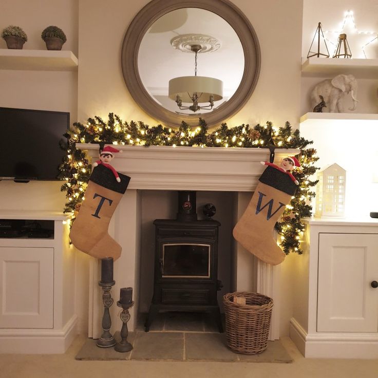 stockings hanging from the mantle in front of a mirror and fireplace with christmas decorations on it