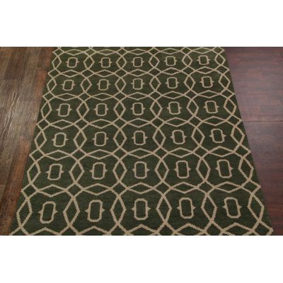 a green rug with an intricate design on the bottom, and a wooden floor in front