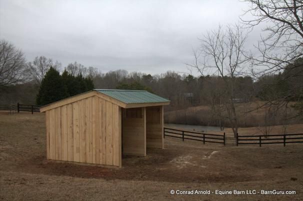 a small wooden shed sitting on top of a dry grass field next to a fence