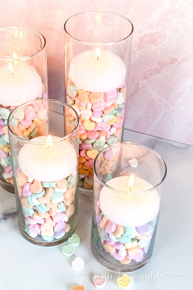 four glass vases filled with marshmallows and candles