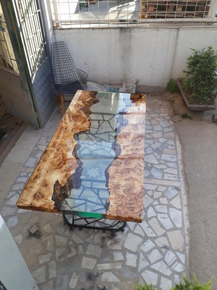 a table made out of wood and glass sitting on a stone floor next to a building