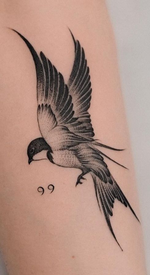 a black and white bird tattoo on the arm