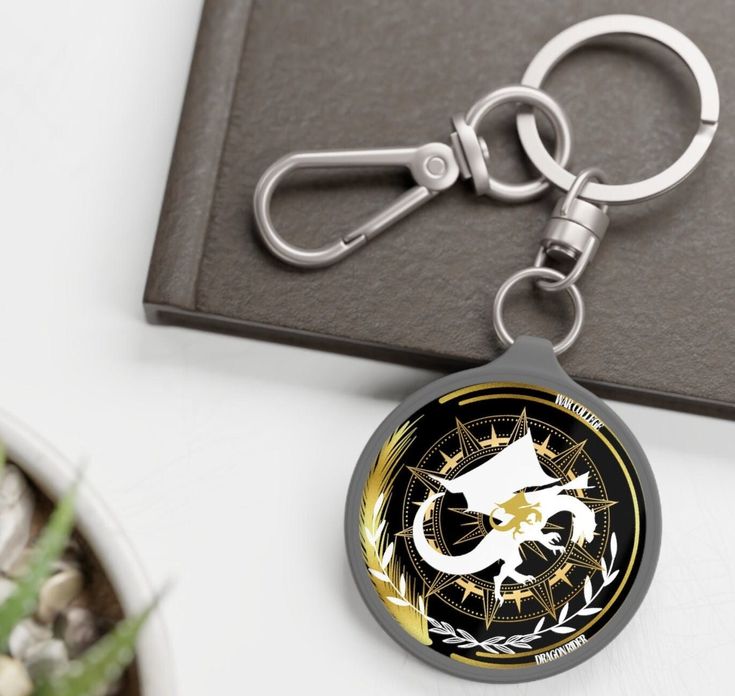 a metal keychain with an image of a cat on it sitting next to a potted plant